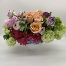 Peach roses and pink hydrangeas in a white vase with green blooms