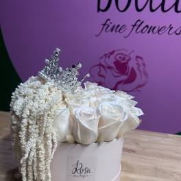 White roses in a round box with a silver tiara and draping white filler