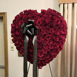 Heart-shaped arrangement of red roses with a black ribbon bow