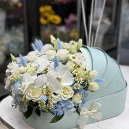 White and pale blue floral arrangement in a mint gift box