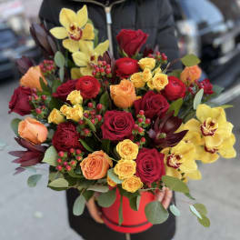 Bouquet of red, yellow, and peach roses with yellow orchids