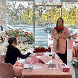 Two women in a flower shop with bouquets and roses on a table