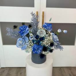 Blue rose arrangement in a gray hatbox with white filler flowers