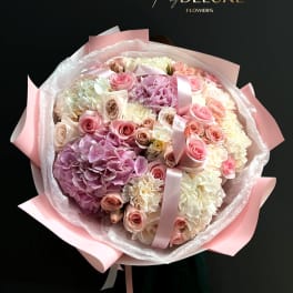 Large bouquet of pink and white roses and hydrangeas wrapped in pink paper