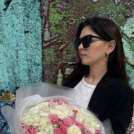 Woman holding a bouquet of pink and white flowers wrapped in translucent paper