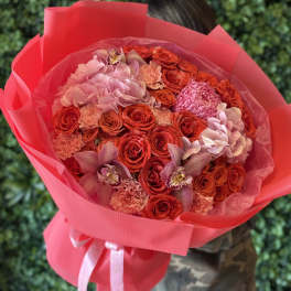 Large bouquet of red and pink roses with orchids wrapped in bright pink paper