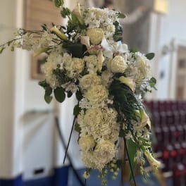 Large white floral cross arrangement on a stand