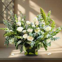 White roses and green blooms in a square glass vase