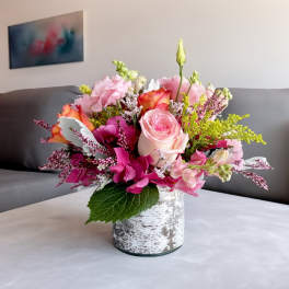 Pink and peach floral arrangement in a white textured vase