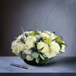 Low round arrangement of white roses and hydrangeas in a dark green bowl