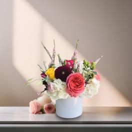 Mixed bouquet of pink, white, and yellow flowers in a white vase