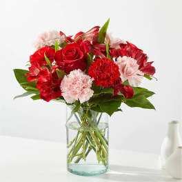 Red roses and pink carnations in a clear glass vase