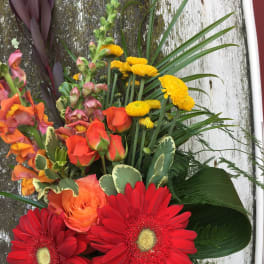 Bright mixed bouquet with red gerbera daisies, orange roses, and yellow blooms