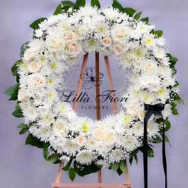 White floral wreath on an easel with a black ribbon