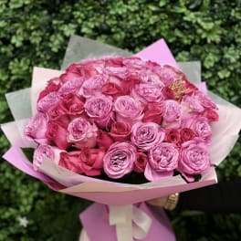 Bouquet of pink roses wrapped in pastel paper with a ribbon