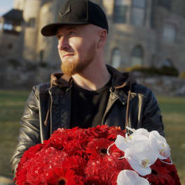 Large red floral arrangement in a black hatbox with white orchids and pearl strands