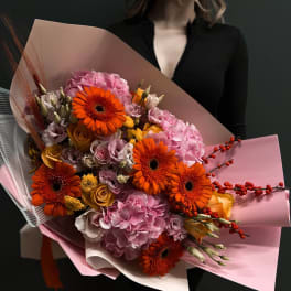 Large bouquet of orange gerbera daisies and pink hydrangeas wrapped in pink paper