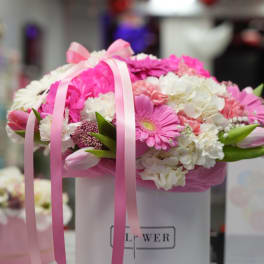 Pink and white flower arrangement in a white hatbox with ribbon