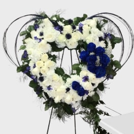 Heart-shaped floral wreath on a stand with white and blue roses