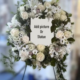 White floral wreath on an easel with a center space for a photo or statue