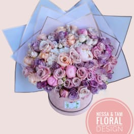 Large bouquet of pink and lavender roses in a round box