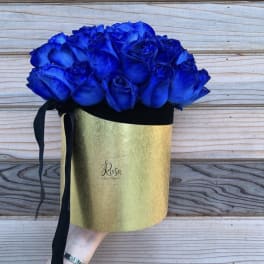 Blue roses in a gold hatbox with a black ribbon