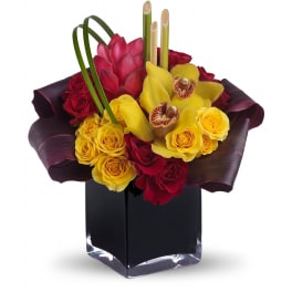 Compact arrangement of yellow roses and orchids with red flowers in a black glass cube vase