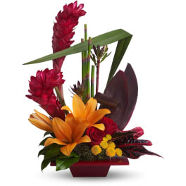 Modern tropical arrangement with orange lilies, red roses, red ginger, yellow blooms, and bamboo in a red container