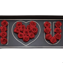 Red roses arranged to spell I heart U in a black box
