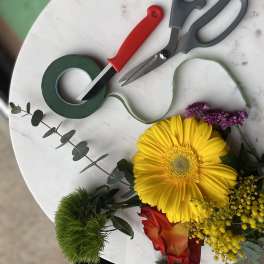 Floral arranging tools and a small bouquet with a yellow gerbera daisy