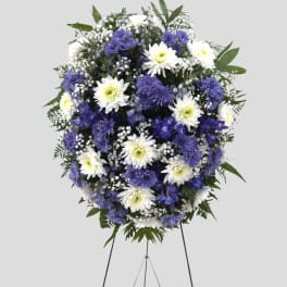Standing floral wreath of white and purple flowers on an easel