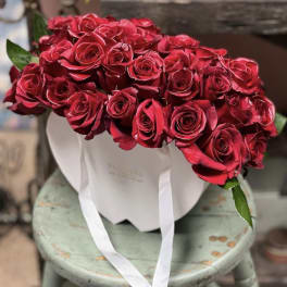 Bouquet of red roses in a white hatbox with white ribbon