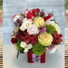 Mixed bouquet of roses and red flowers in a gift box