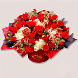 Red roses and white hydrangeas arranged in a round gift box