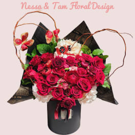 Bouquet of red roses and white hydrangeas in a black box with butterfly accents