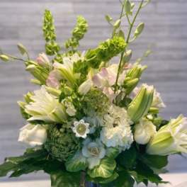 White and pale green floral arrangement in a dark vase