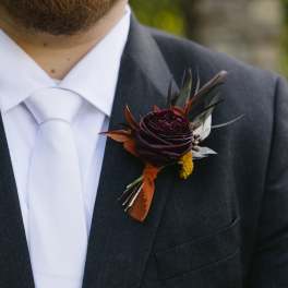Dark floral boutonniere pinned to a black suit jacket