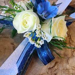 White roses with a blue flower and ribbon accents