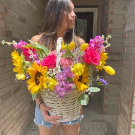 Woman holding a wicker basket filled with bright mixed flowers
