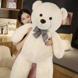 Woman holding a large white teddy bear with a checkered bow