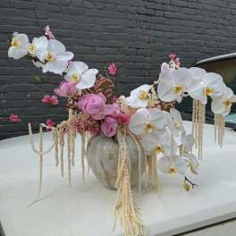 Pink and white orchid arrangement in a ceramic vase