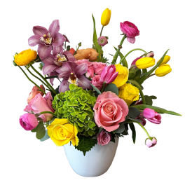 Mixed bouquet of pink, yellow, and purple flowers in a white vase