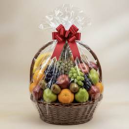 Large wicker gift basket filled with assorted fresh fruit wrapped in cellophane with a red bow