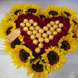 Heart-shaped bouquet of red roses and sunflowers with gold chocolates in the center