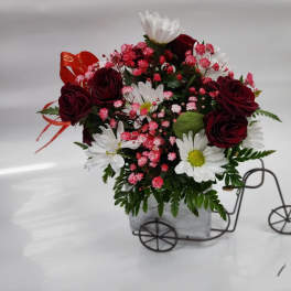Bouquet of red roses and white daisies in a small bicycle planter