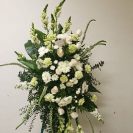 White and pale green floral standing spray on a green easel