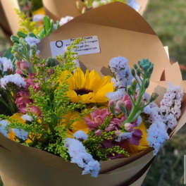 Mixed bouquet with a yellow sunflower and pink flowers in brown paper