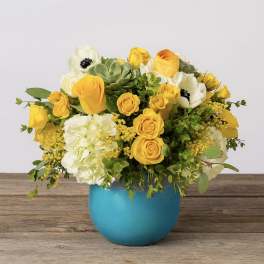 Yellow and white flower arrangement in a blue vase