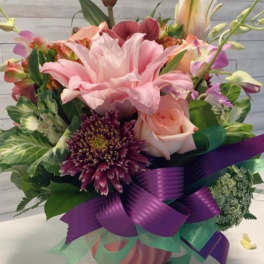 Pink lily and rose bouquet with purple ribbon in a vase