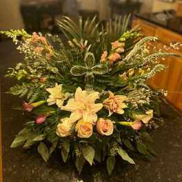Large floral arrangement with lilies and roses in a low container